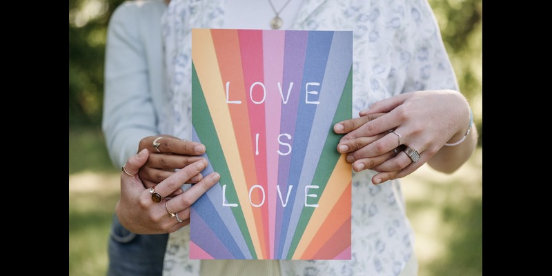 A couple holding a poster to commemorate LGBTQ+ and pride celebrations. 