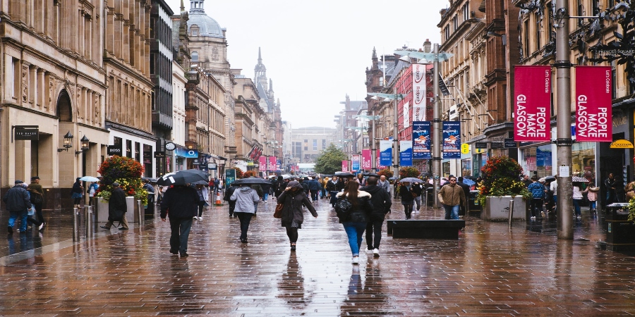 Glasgow Rainy Day: Tourists strolling through charming streets, umbrellas in hand, capturing the city's allure in a gentle shower.