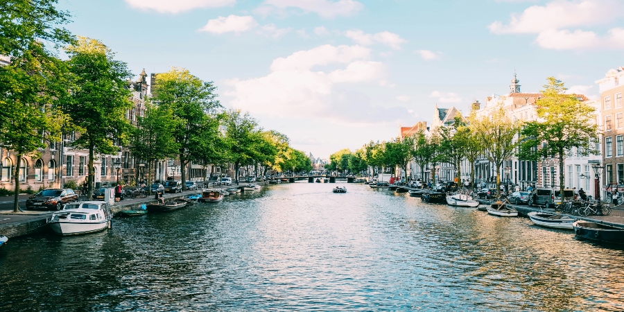 Amsterdam's picturesque canals lined with historic buildings and vibrant flowers - a delightful summer destination in Europe.